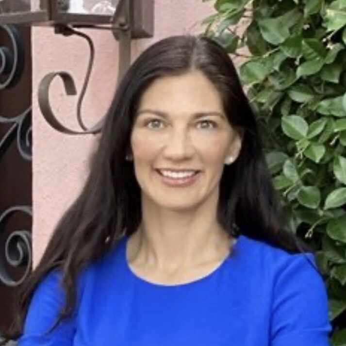 A woman in blue shirt smiling for the camera.